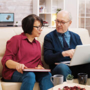 a couple using laptop and sitting on a sofa
