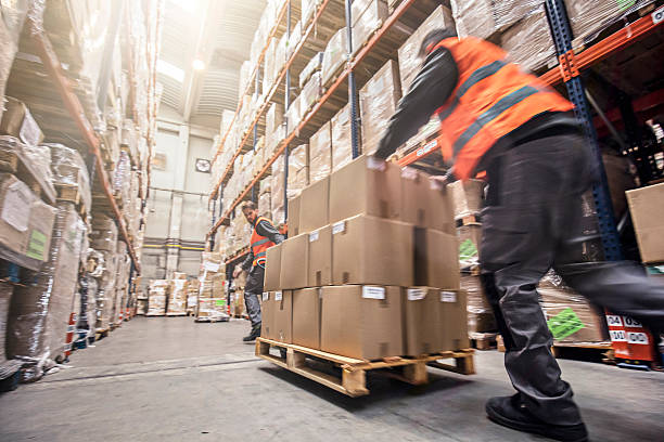 Motion blur of two men moving storage boxes in a warehouse.