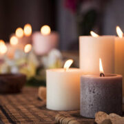 Closeup of burning candles spreading aroma on table in a spa room. Beautiful composition with grey and white candles for spa treatment. Zen and relax concept.