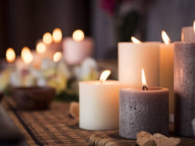 Closeup of burning candles spreading aroma on table in a spa room. Beautiful composition with grey and white candles for spa treatment. Zen and relax concept.